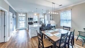 A modern kitchen with white cabinetry, a central island, and pendant lighting. - 3 BR/4BA with ADDITIONAL Kids bunk room. (Greensboro)