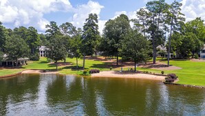 A golf course with a pond, trees, and buildings in the background. - 3 BR/4BA with ADDITIONAL Kids bunk room. (Greensboro)