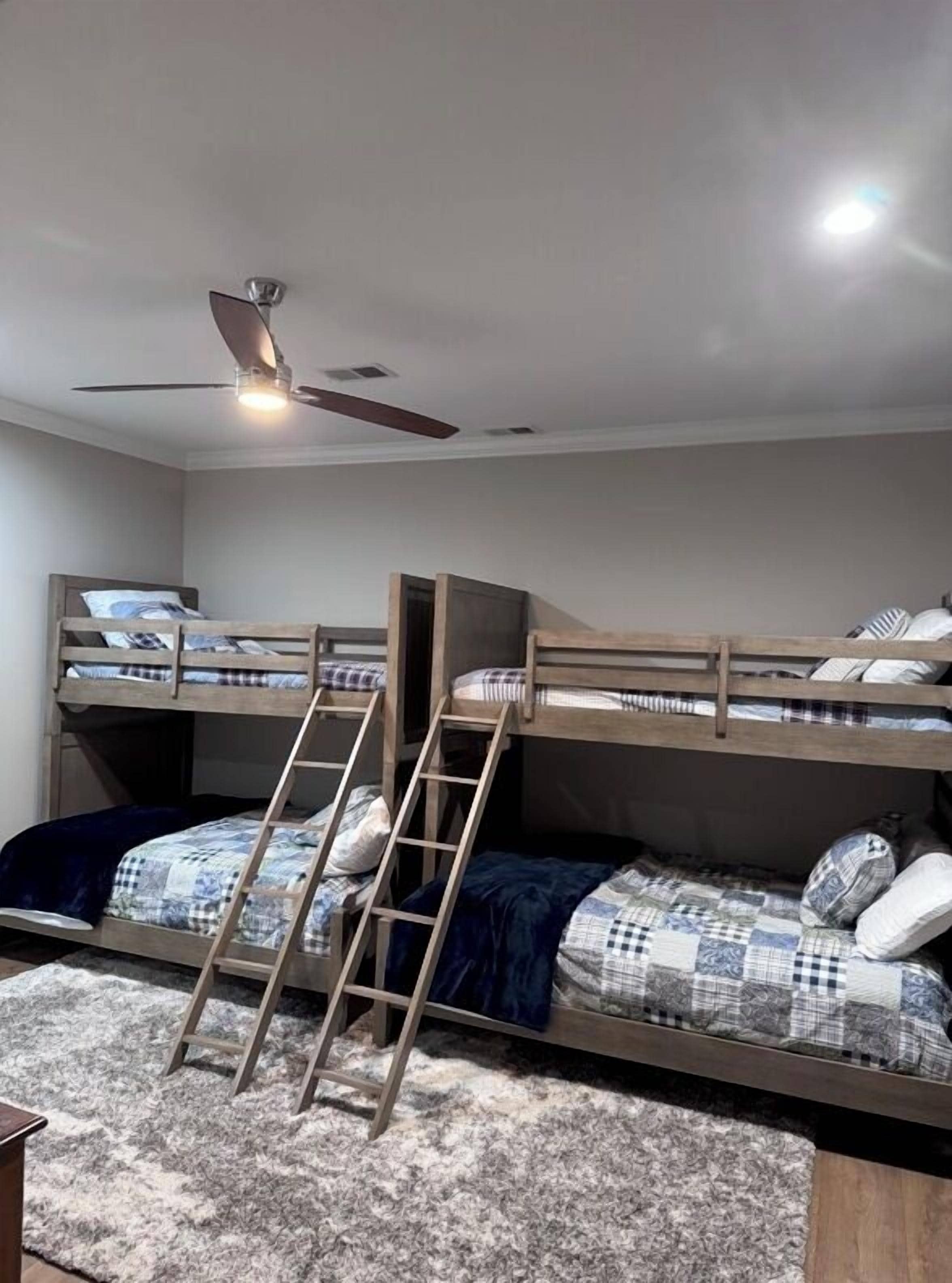 Camera con letto a castello, scala, ventola a soffitto e tappeto.