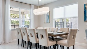 Une salle à manger avec une table ronde, six chaises et un lustre.
