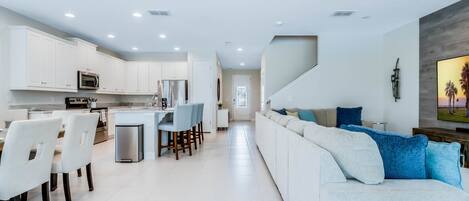A modern kitchen with white cabinets, stainless steel appliances, and a central island with bar stools.