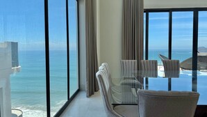 A room with a large window overlooking the ocean, a glass table, and two chairs. - The O  (Mazatlán)