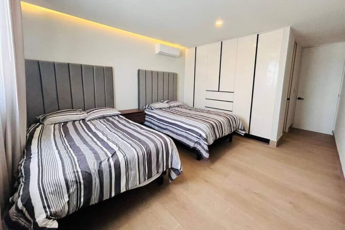 Un dormitorio moderno con dos camas, un armario y una lámpara de techo.