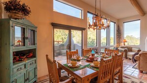 A dining area with a wooden table set for six, surrounded by chairs, with a cabinet and a chandelier above. - Castle Rock Abode | Private Sedona Retreat w/ Trail Access, Fire Pit & BBQ (Sedona)
