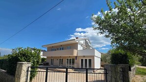 A two-story house with a balcony, a gated entrance, and a clear sky. - Studio-apartment Letizia (Rasopasno)