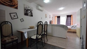 A small, cozy room with a dining area, a bed, and a kitchenette. - Studio-apartment Letizia (Rasopasno)