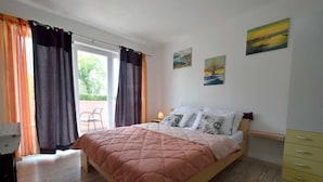 A bedroom with a bed, a nightstand, a chair, and a window with curtains. - Studio-apartment Letizia (Rasopasno)