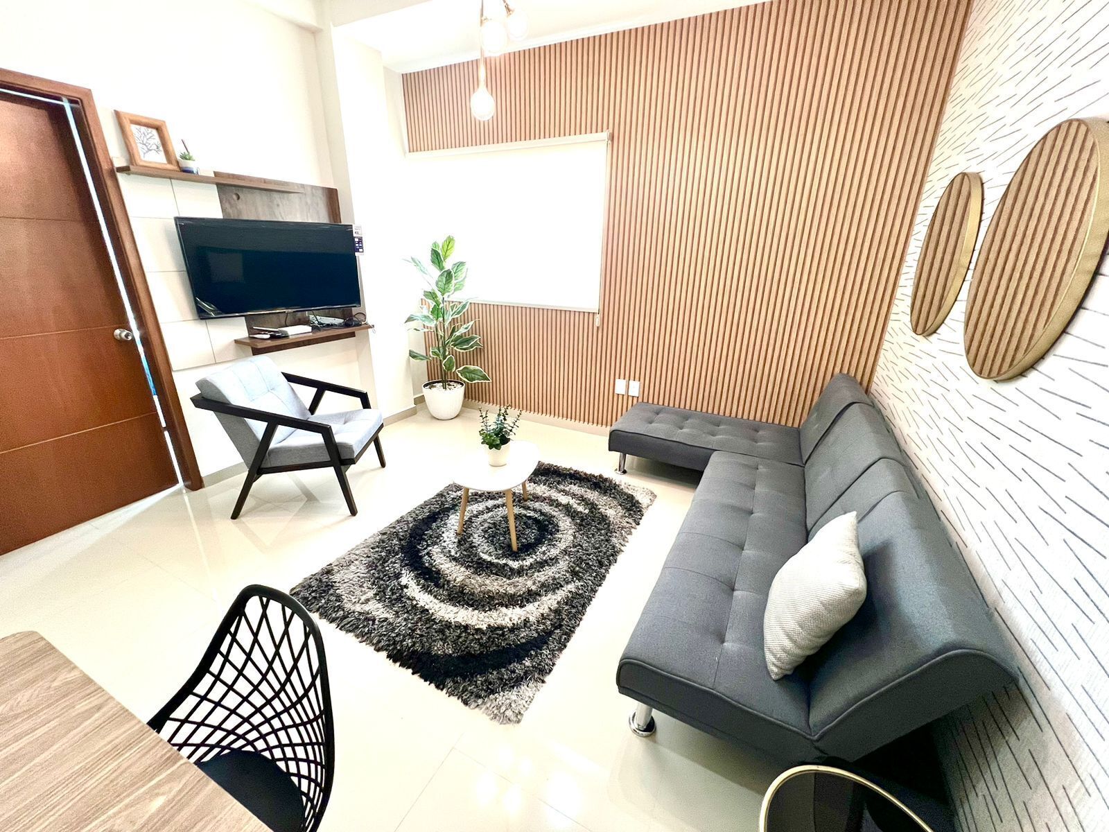 Un salon moderne avec un canapé, un téléviseur, une table à manger et une plante en pot.