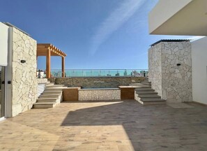 A rooftop terrace with stone walls, a pergola, and a view of the sea. - Matthay (Mazatlán)