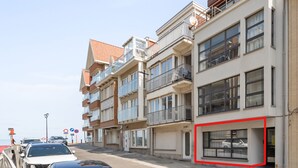 Una fila di edifici moderni a più piani con balconi, un'area parcheggio e cielo sereno.