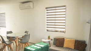 Una sala de estar moderna con una mesa redonda, sillas, un sofá y un pouf verde.