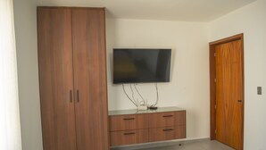 Una habitación con un armario de madera, un televisor de pantalla plana en la pared y una puerta de madera.