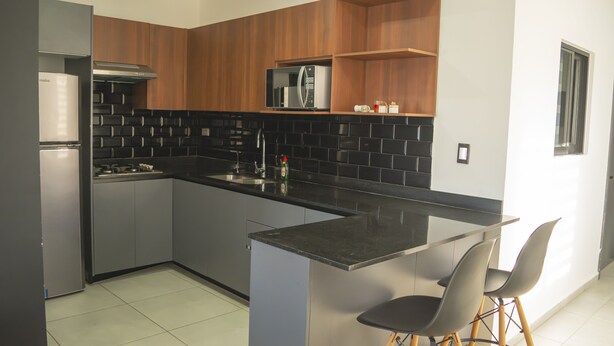 Una cocina moderna con refrigerador, estufa, microondas y una pequeña isla con sillas.