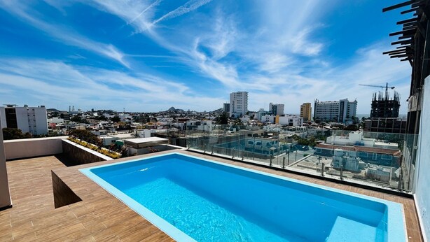 A rooftop pool with a clear view of the cityscape in the background. - Flamingos (Mazatlán)