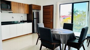 A modern kitchen with white cabinets, a stainless steel refrigerator, and a dining area with a round table and four chairs. - Flamingos (Mazatlán)