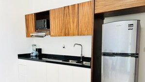 A modern kitchen with white cabinets, a stainless steel refrigerator, a microwave, and a built-in oven. - Flamingos (Mazatlán)