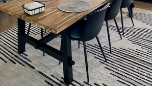 A dining area with a wooden table, black chairs, and woven placemats. - Water’s Edge - Ocean views, Private hot tub (Bodega Bay)
