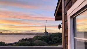 A wooden balcony with a view of a body of water and a distant building. - Water’s Edge - Ocean views, Private hot tub (Bodega Bay)