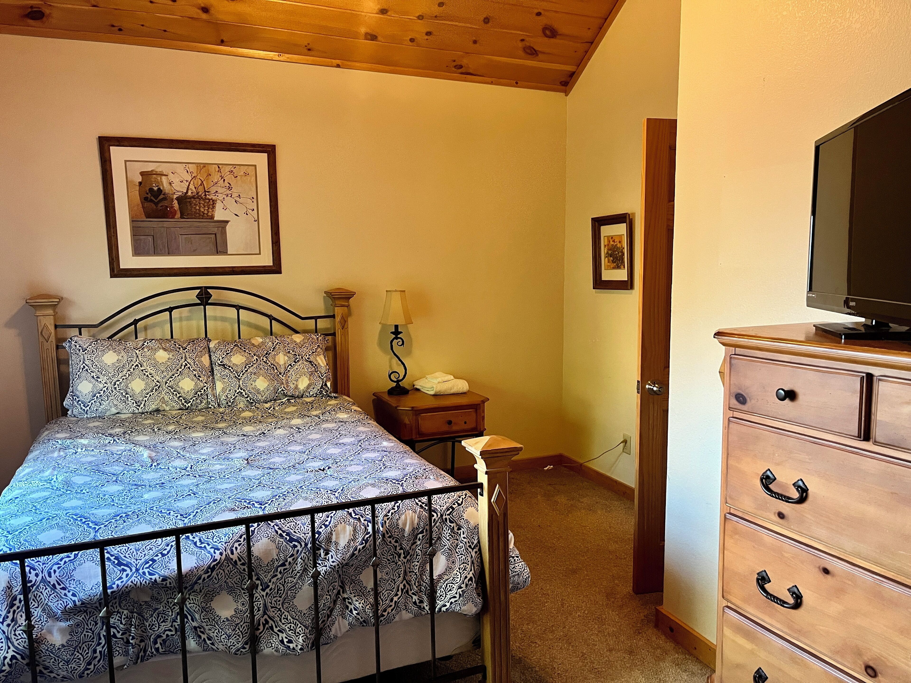 A bedroom with a bed, a dresser, a television, and a lamp.