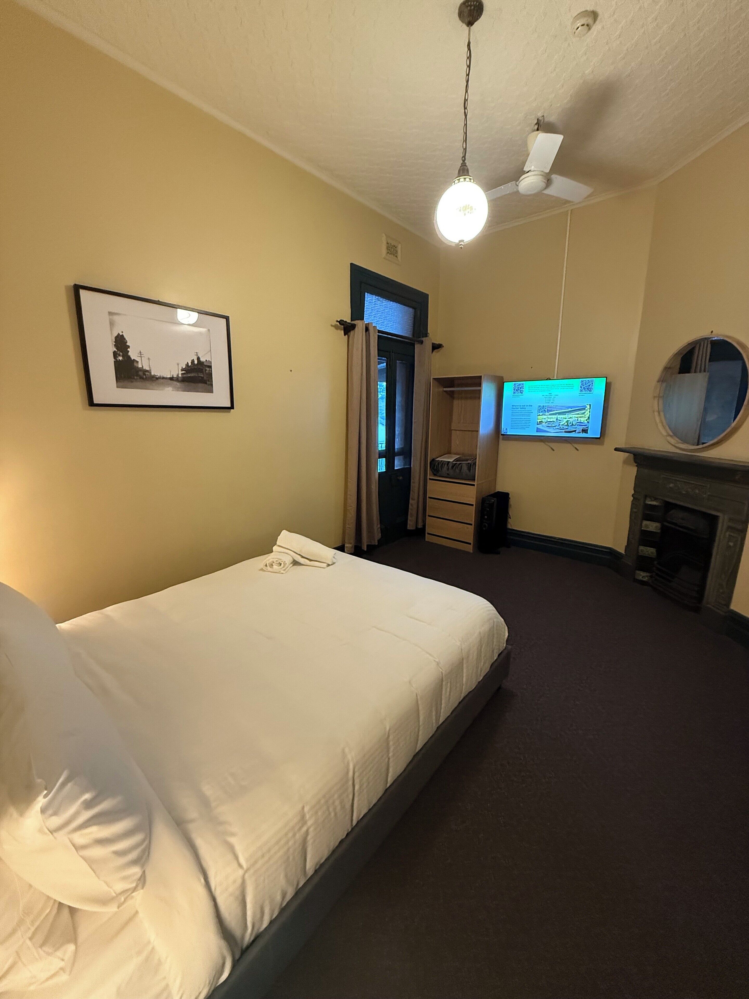 Ein Hotelzimmer mit Bett, Deckenventilator, Fernseher, Kamin und einem gerahmten Bild an der Wand.