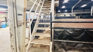 A metal staircase leading to a fenced area, with a sign indicating 'REST ROOMS' on the wall. - Perfect place to stay for events at the Lazy E (Guthrie)
