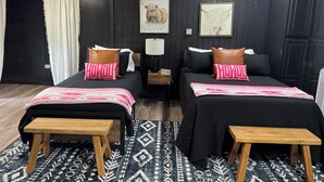 A bedroom with two beds, a nightstand, a lamp, and a window with curtains. - Perfect place to stay for events at the Lazy E (Guthrie)