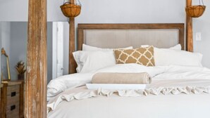 A neatly made bed with white and beige bedding, a wooden headboard, and a hanging basket on each side. - Current Bungalow 5 Beds Pro Turnkey MP Getaways (Clarksville)