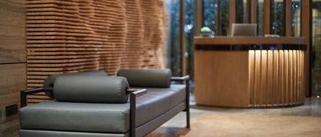 A modern interior with a sofa, a wooden reception desk, and a patterned wall.