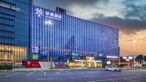 A modern hotel with a glass facade and illuminated signage. - HuaMan Hotel DongGuan TangXia (Dongguan)