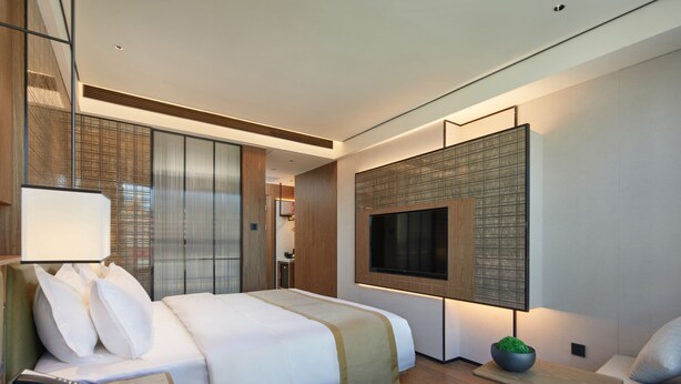 A modern hotel room with a large bed, bedside table, and a TV mounted on the wall. - HuaMan Hotel DongGuan TangXia (Dongguan)