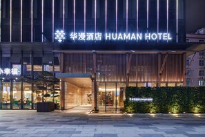 The exterior of the Huaman Hotel with a modern facade, illuminated signage, and a well-lit entrance area. - HuaMan Hotel DongGuan TangXia (Dongguan)