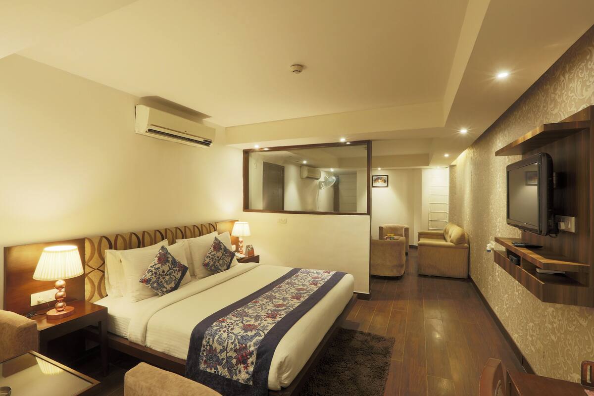 Een hotelkamer met een bed, nachtkastjes, een televisie, een bank en een spiegel.