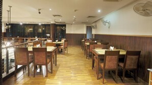 Ein Restaurant mit Holzboden, mehreren Tischen und Stühlen, Deckenventilatoren und Einbauleuchten.