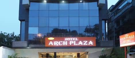 A hotel with a modern facade, a prominent sign reading 'ARCH PLAZA HOTEL,' and a staircase leading to the entrance.