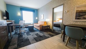 Ein Hotelzimmer mit Schreibtisch, Stuhl, Sofa und einem Bett.