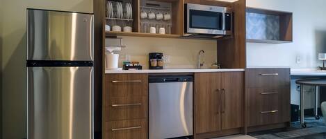 A modern kitchen with a stainless steel refrigerator, a microwave, wooden cabinets, and a dishwasher.