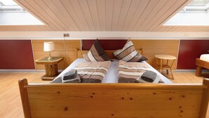 Una cama doble con ropa de cama a rayas, una lámpara de noche y una pequeña mesa redonda.