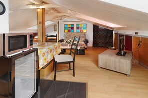 A compact kitchen with a microwave, refrigerator, and a dining area with a table and chairs.
