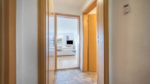 A hallway with a wooden door leading to a bedroom with a bed and a TV. - 'Knopf' Holiday Apartment with Balcony and Wi-Fi (Hardegsen)