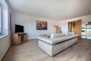 Ein modernes Wohnzimmer mit einer Couch, Fernseher, Holzschrank und Kunstwerken an der Wand.