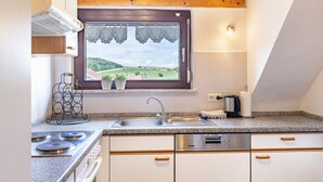 Eine Küche mit Herd, Spüle und Fenster mit Blick auf eine Landschaft.