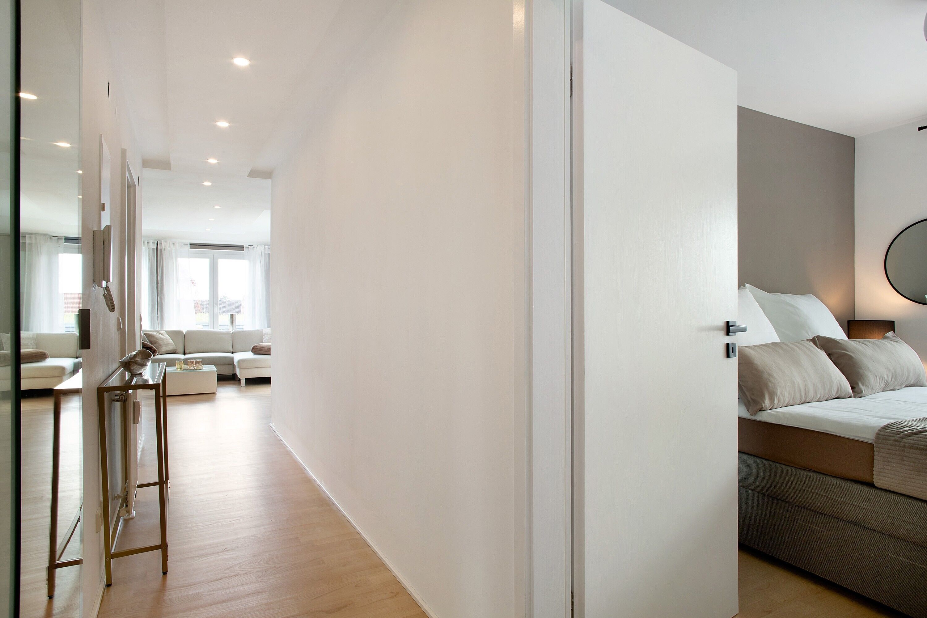 A modern hotel room with a bed, bedside table, and a view of the living area.