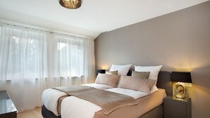 A bedroom with a bed, bedside tables, a lamp, and a window with curtains.