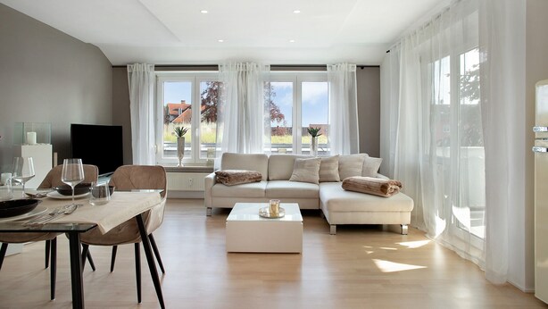 A modern living room with a sofa, coffee table, and dining area.