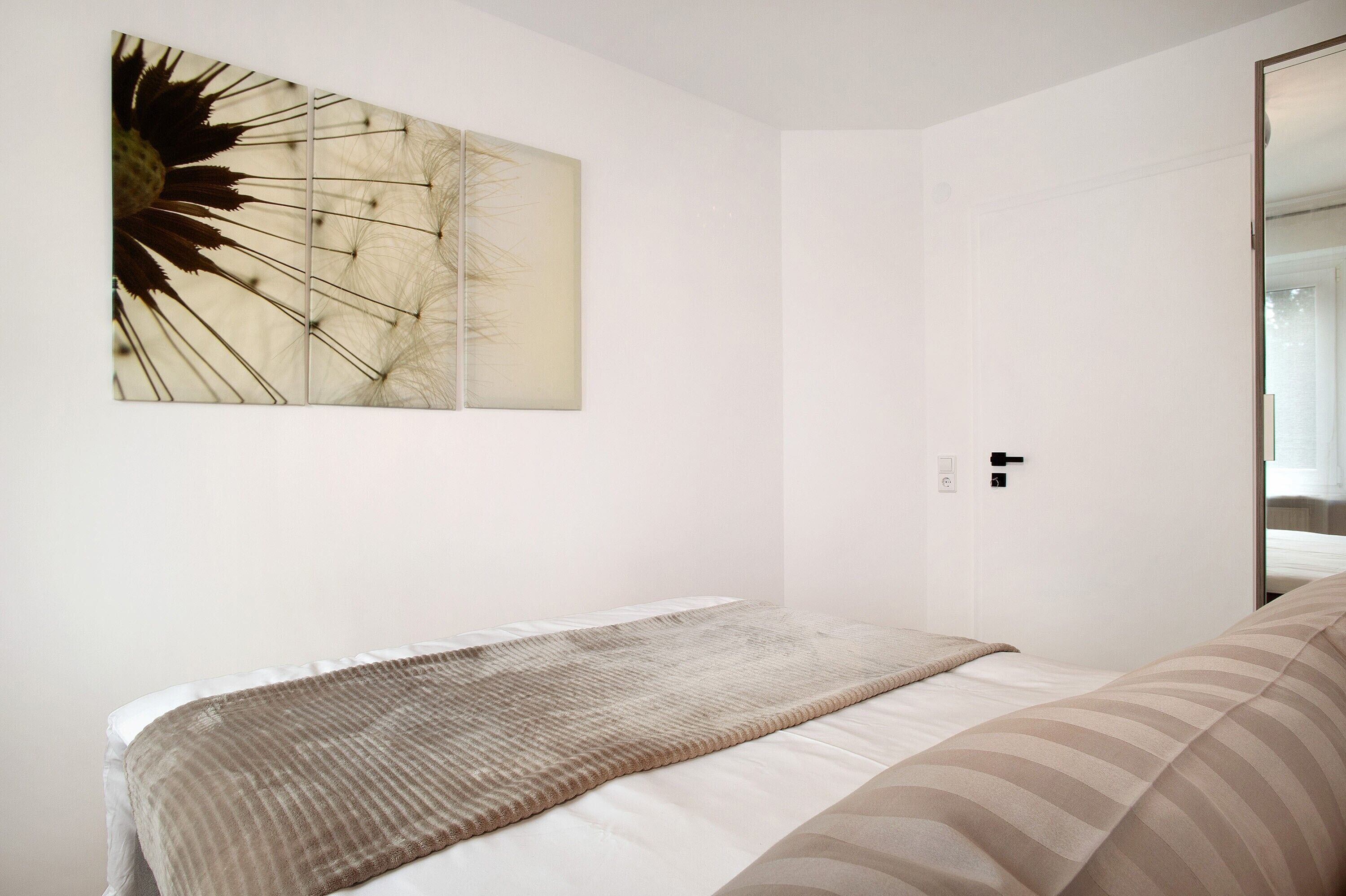 Un dormitorio con cama, una obra de arte en la pared y una puerta.