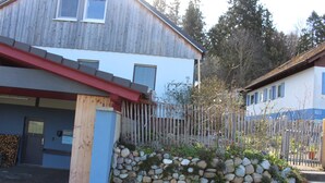Un edificio con fachada de madera, pared de piedra y cerca de metal.