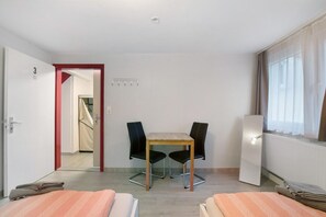 Una habitación de hotel con cama, una mesa con sillas, una puerta y una ventana.