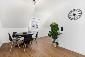 En spiseplads med et rundt bord, stole, en potteplante og et vægur.