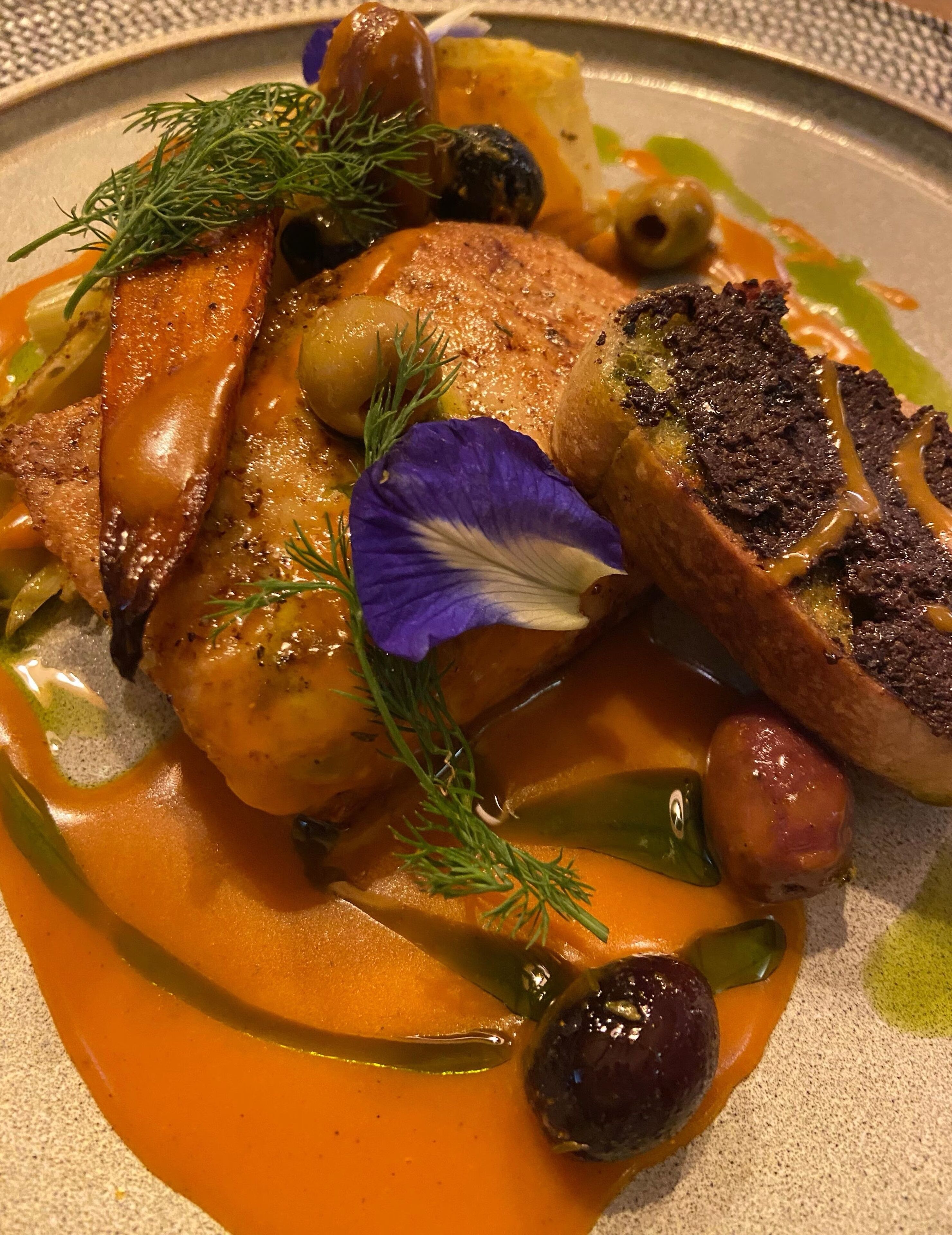 Un plato de comida con pollo asado, verduras y salsa.