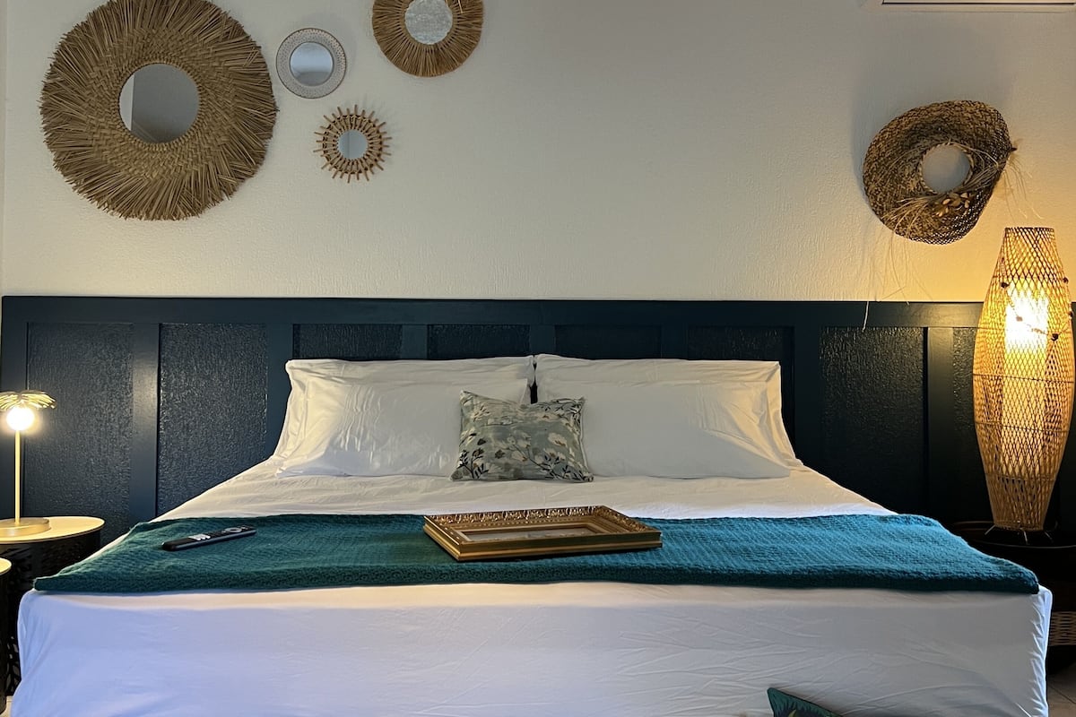 A bedroom with a bed, a nightstand, a lamp, and wall decorations.